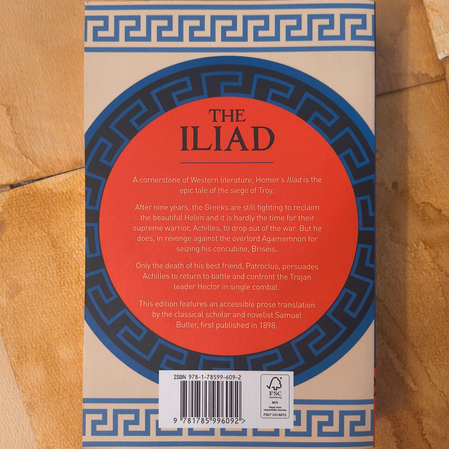 Book titled 'The Iliad' with a red circular design on a brown background