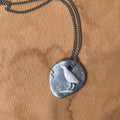 Silver necklace with a pendant featuring a bird design on a brown surface