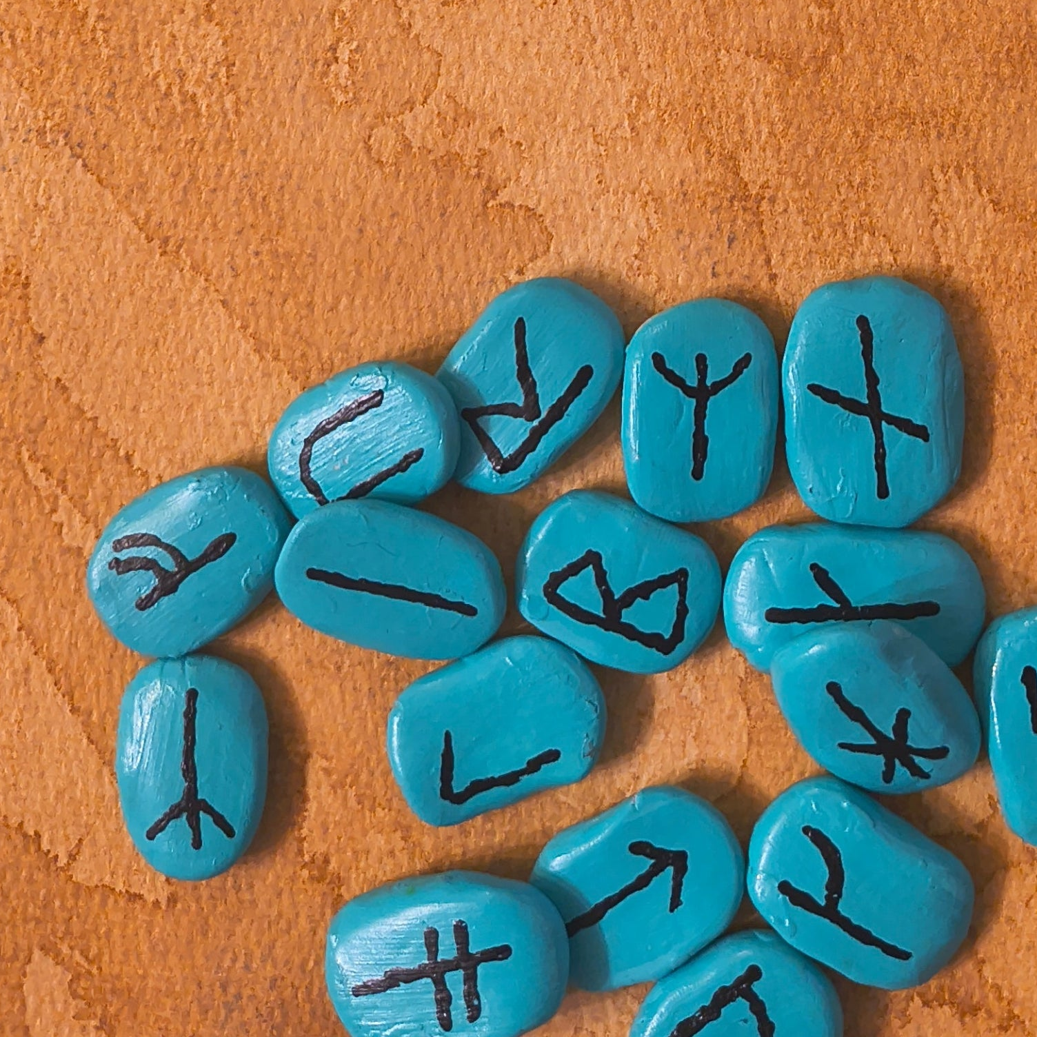 Turquoise stones with black symbols on a brown surface