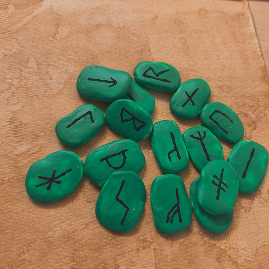 Green stones with black symbols on a brown surface